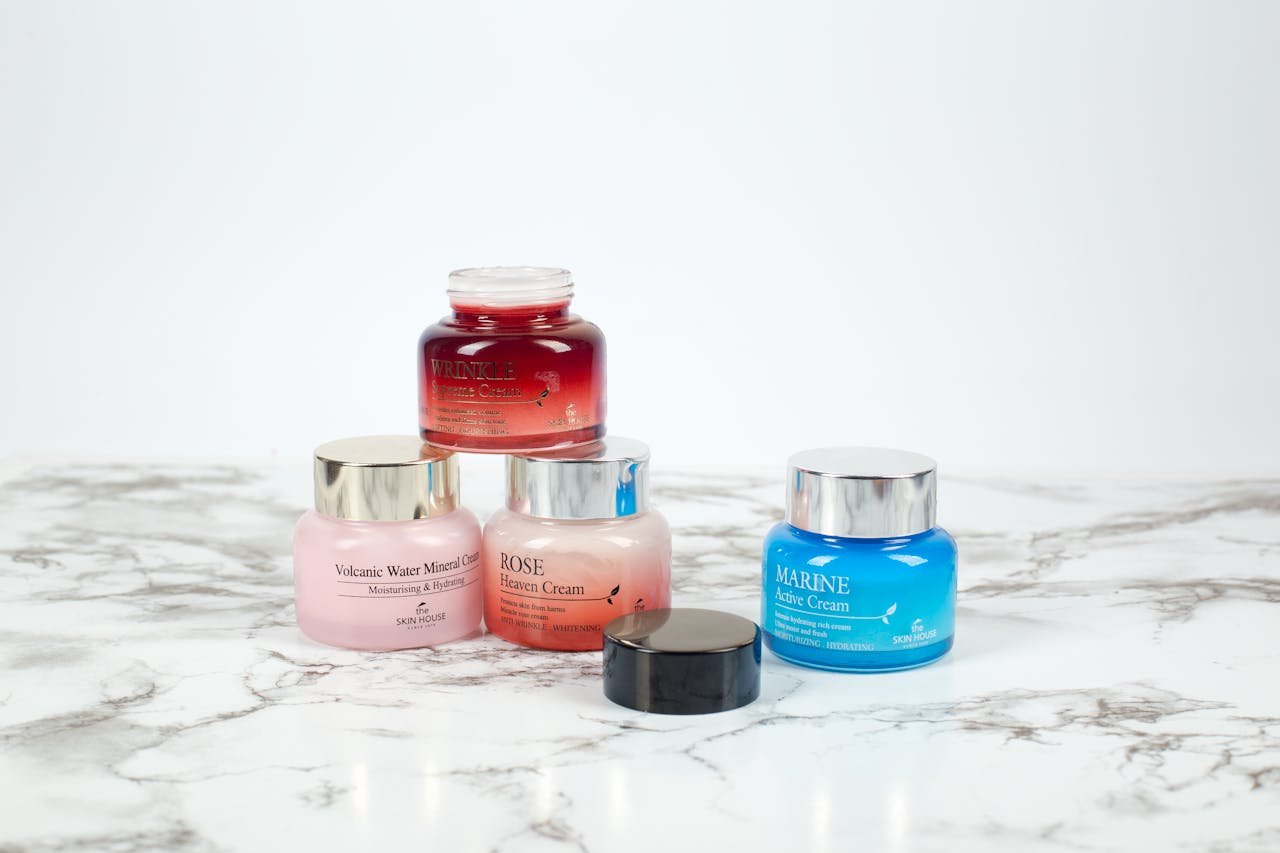 Assorted skincare cream jars arranged on a marble surface, showcasing beauty and elegance.